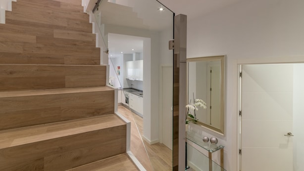 Un escalier moderne avec des marches en bois menant à un espace cuisine.