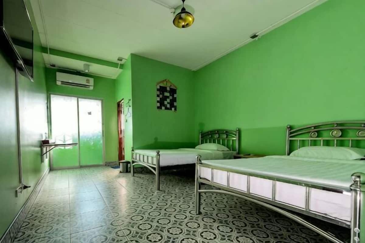 A room with two beds, a window, and a checkered wall decoration.