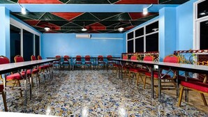 Ein Konferenzraum mit blauer Wand, roten Stühlen, einem langen Tisch und einem gemusterten Boden.