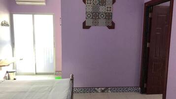 Una habitación con una cama, un azulejo decorativo en la pared, una puerta y una ventana.