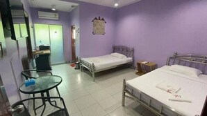 Ein Hotelzimmer mit zwei Einzelbetten, einem kleinen Tisch, einem Stuhl, einem Schreibtisch und einem Kleiderschrank.