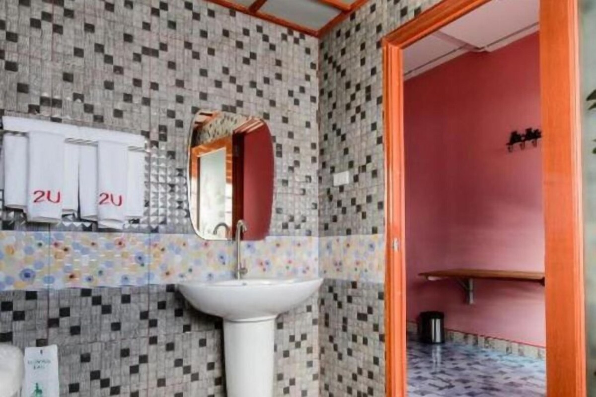 A bathroom with a tiled wall, a sink, and a mirror.