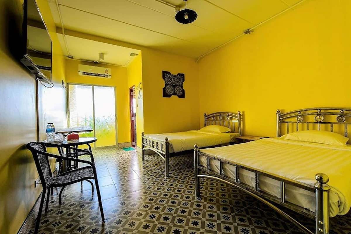 A room with two beds, a table with chairs, and a patterned floor.