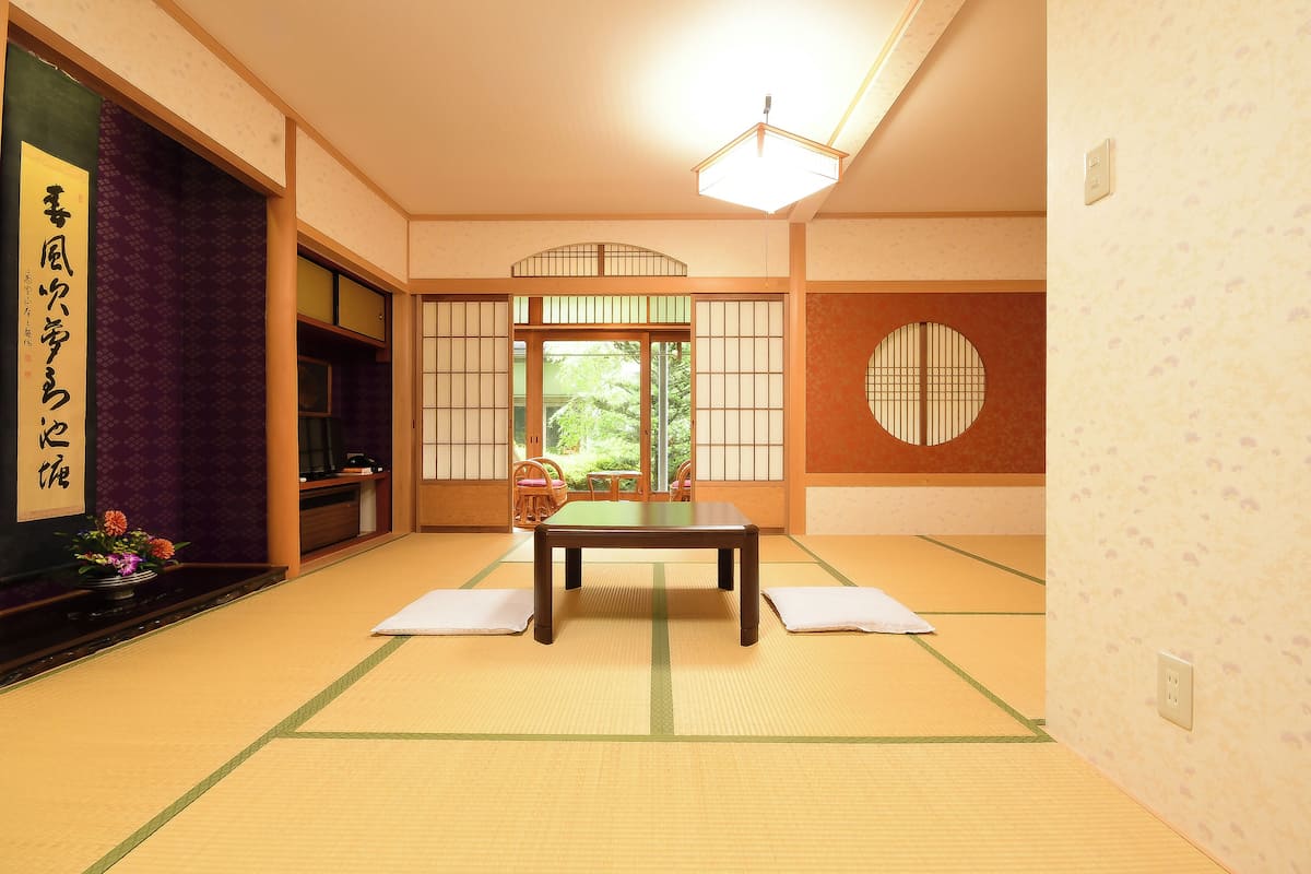 A traditional Japanese room with tatami flooring, a low table, and shoji screens.