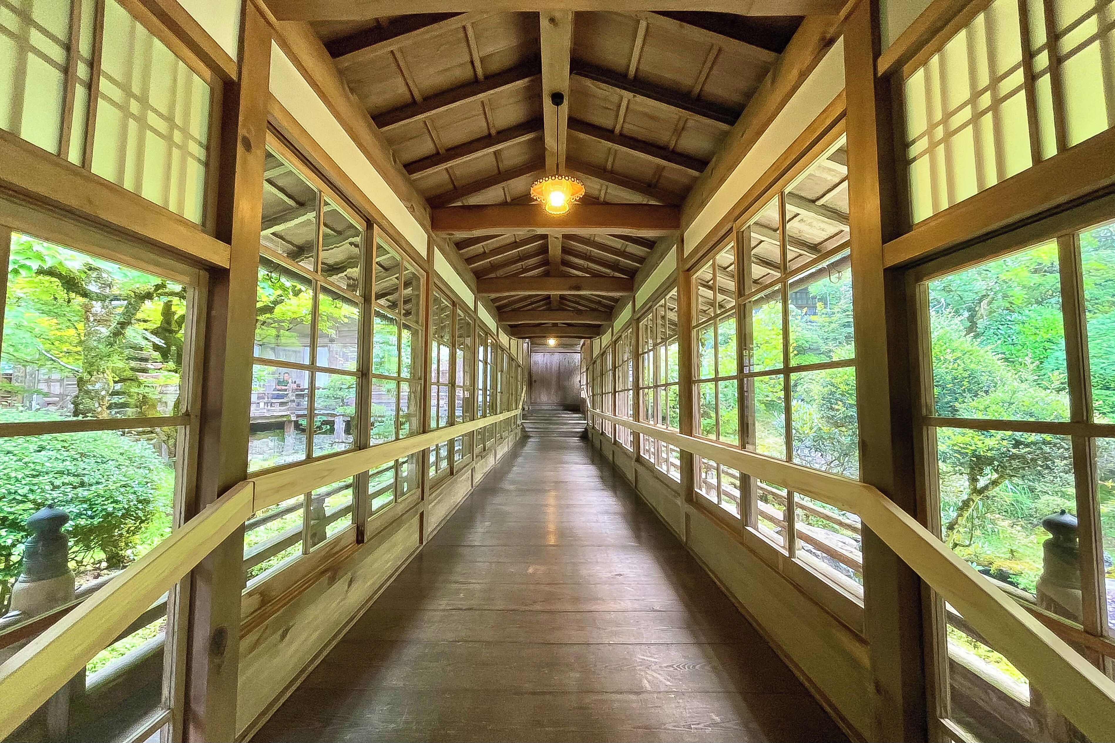 A covered wooden walkway with large windows and a central light fixture.