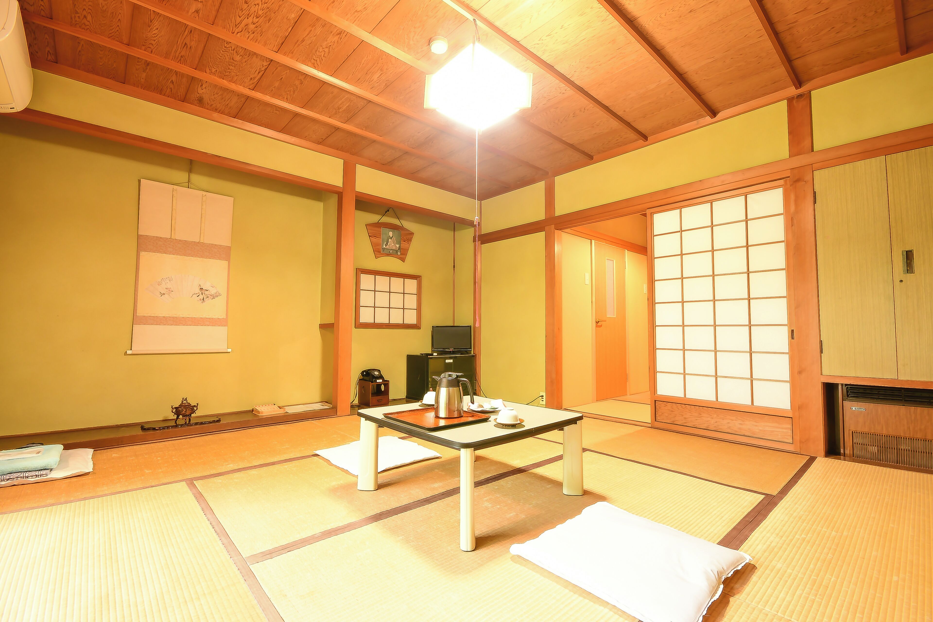 Ein traditioneller japanischer Raum mit Tatami-Bodenbelag, einem niedrigen Tisch mit Wasserkocher und Schiebetüren.