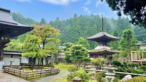A traditional Japanese garden with a pagoda, stone lanterns, and a wooden fence. - Kongo Sanmaiin (Koya)