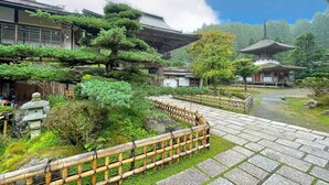 A traditional Japanese temple with a stone pathway, bamboo fence, and lush greenery. - Kongo Sanmaiin (Koya)