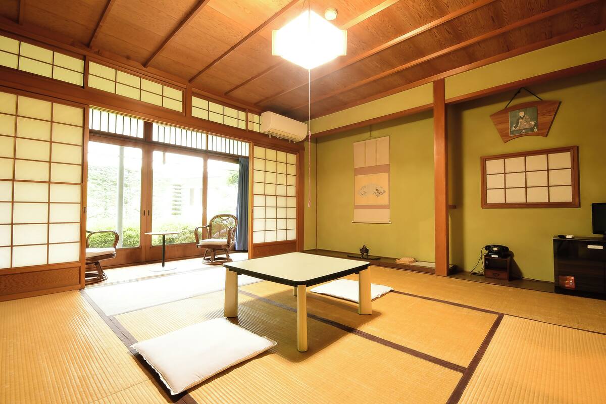 A tatami mat room with a low table, a sofa, and sliding doors leading to a garden.