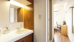 Ein Hotelbad mit einem Holzbadezimmermöbel, einem großen Spiegel und einem Waschbecken.