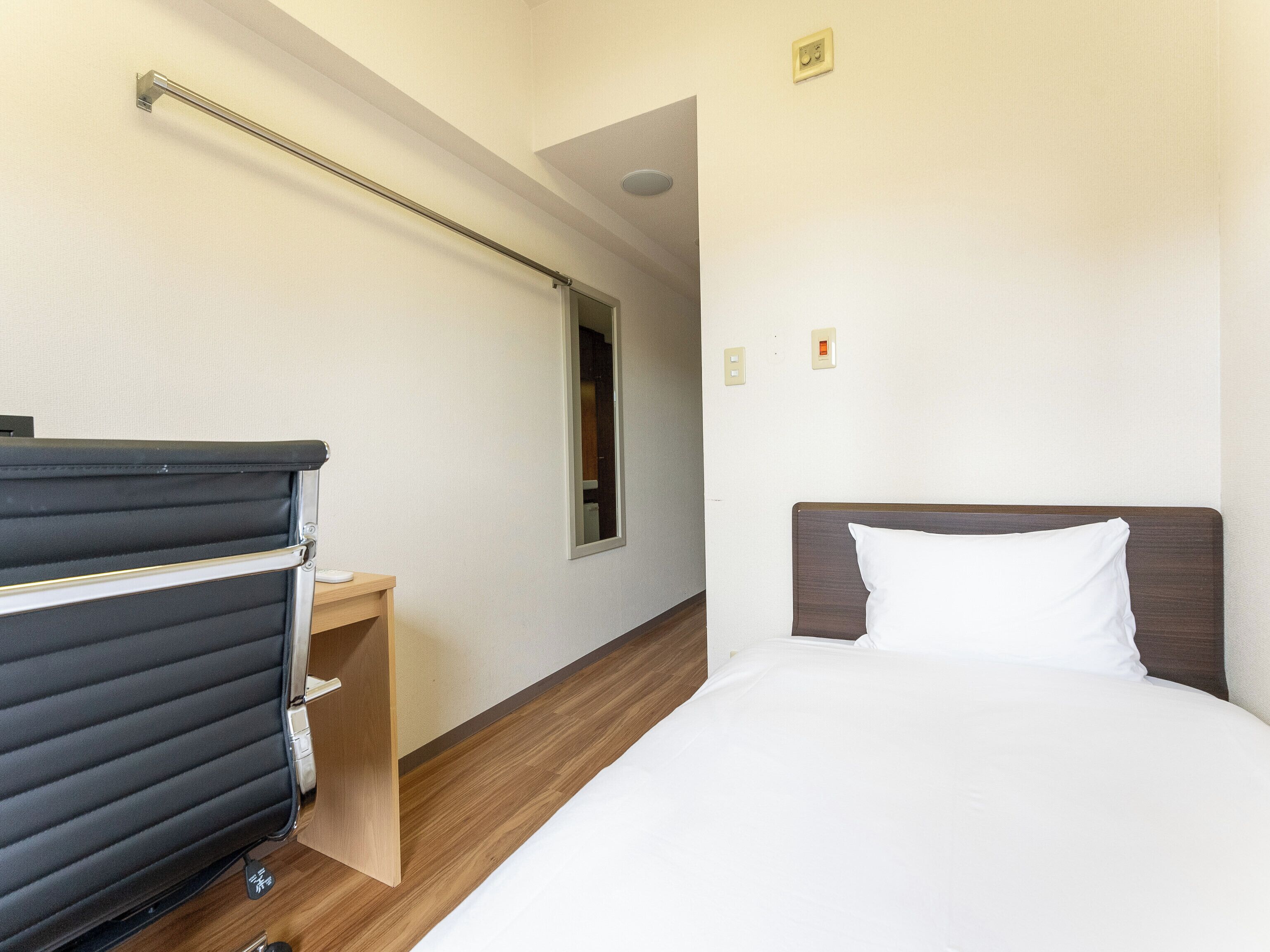 A hotel room with a bed, a desk, and a chair.
