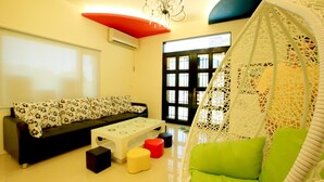 A modern living room with a sofa, a coffee table, a hanging chair, and a large window. - Amethyst Bay 2 (Magong)