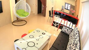 A living room with a flat-screen TV, a hanging chair, a coffee table, and a sofa. - Amethyst Bay 2 (Magong)