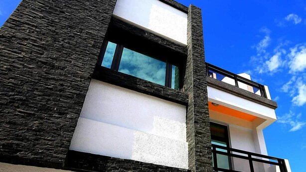 A modern building with a stone facade, large windows, and a balcony. - Amethyst Bay 2 (Magong)