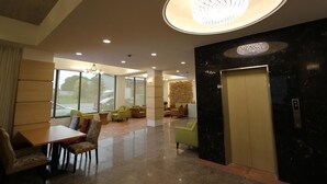 A modern lobby with a reception desk, seating area, and an elevator. - Silia Hostel (Ji'an)