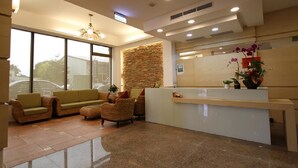 A modern reception area with a stone accent wall, a reception desk, and seating arrangements. - Silia Hostel (Ji'an)