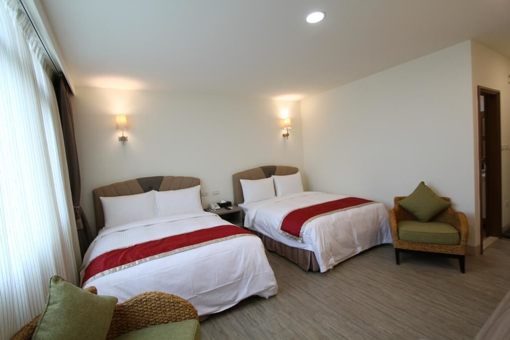 Habitación de hotel con dos camas, una silla y dos luces fijadas a la pared.