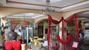 A spacious lobby with a chandelier, red drapes, and modern seating. - RM Guest House (Dumaguete)