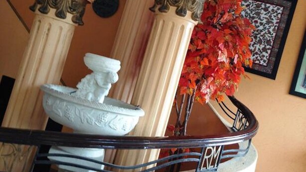 A balcony with ornate columns, a decorative fountain, and a framed artwork on the wall. - RM Guest House (Dumaguete)