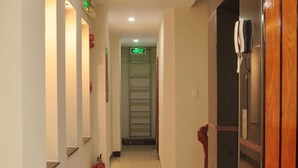 A hotel corridor with a polished floor, a fire extinguisher, and a door with a towel hanging on it.
