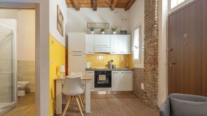 Una cocina funcional con armarios blancos, una mesa de comedor de madera y un sofá gris.