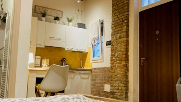 Un dormitorio con cama, escritorio y pared de piedra.