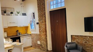 Una sala de estar acogedora con chimenea, un comedor con cocina al fondo y un televisor montado en la pared.