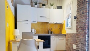 Una cocina moderna con armarios blancos, una mesa de comedor de madera y una pared de acento amarilla.