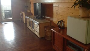 A wooden-paneled room with a television, a small refrigerator, a cabinet, and a wicker basket.
