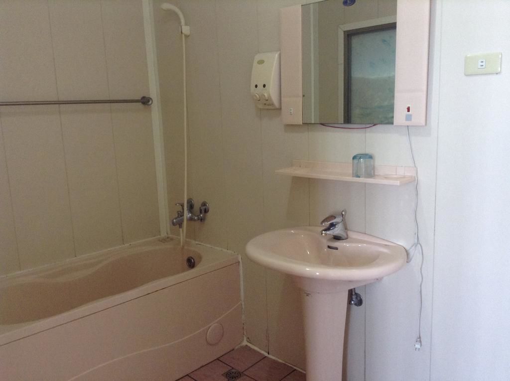 A bathroom with a bathtub, a sink, a mirror, and a soap dispenser.