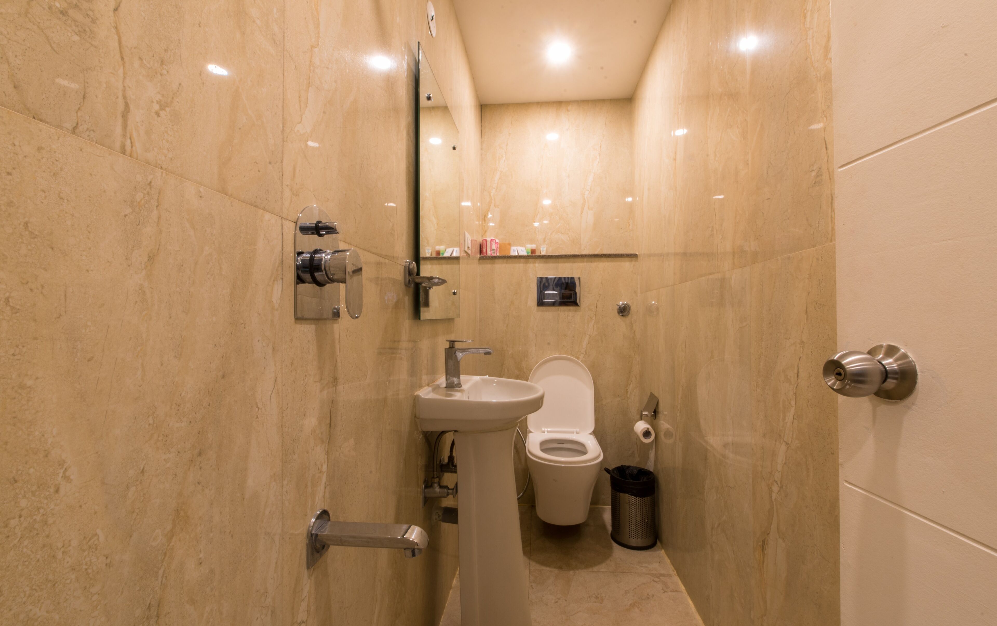 Un baño moderno con lavamanos pedestal, inodoro y espejo.