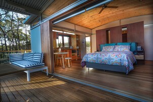 Un dormitorio con cama, escritorio y zona de estar en una terraza.