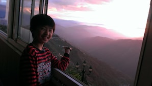 A person standing by a window with a view of a valley and mountains. - Bokelai B&B (Ren'ai)
