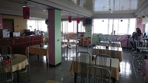 A restaurant with multiple tables and chairs, a counter, and a television screen. - Bokelai B&B (Ren'ai)