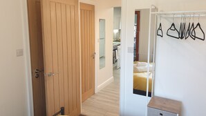 Een slaapkamer met een houten garderobe, een bed met een gele spreidek en een witte nachtkastje.