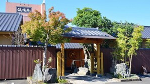 A traditional Japanese building with a tiled roof, a wooden entrance, and a stone pathway leading to the door. - Yuyuan (Kirishima)