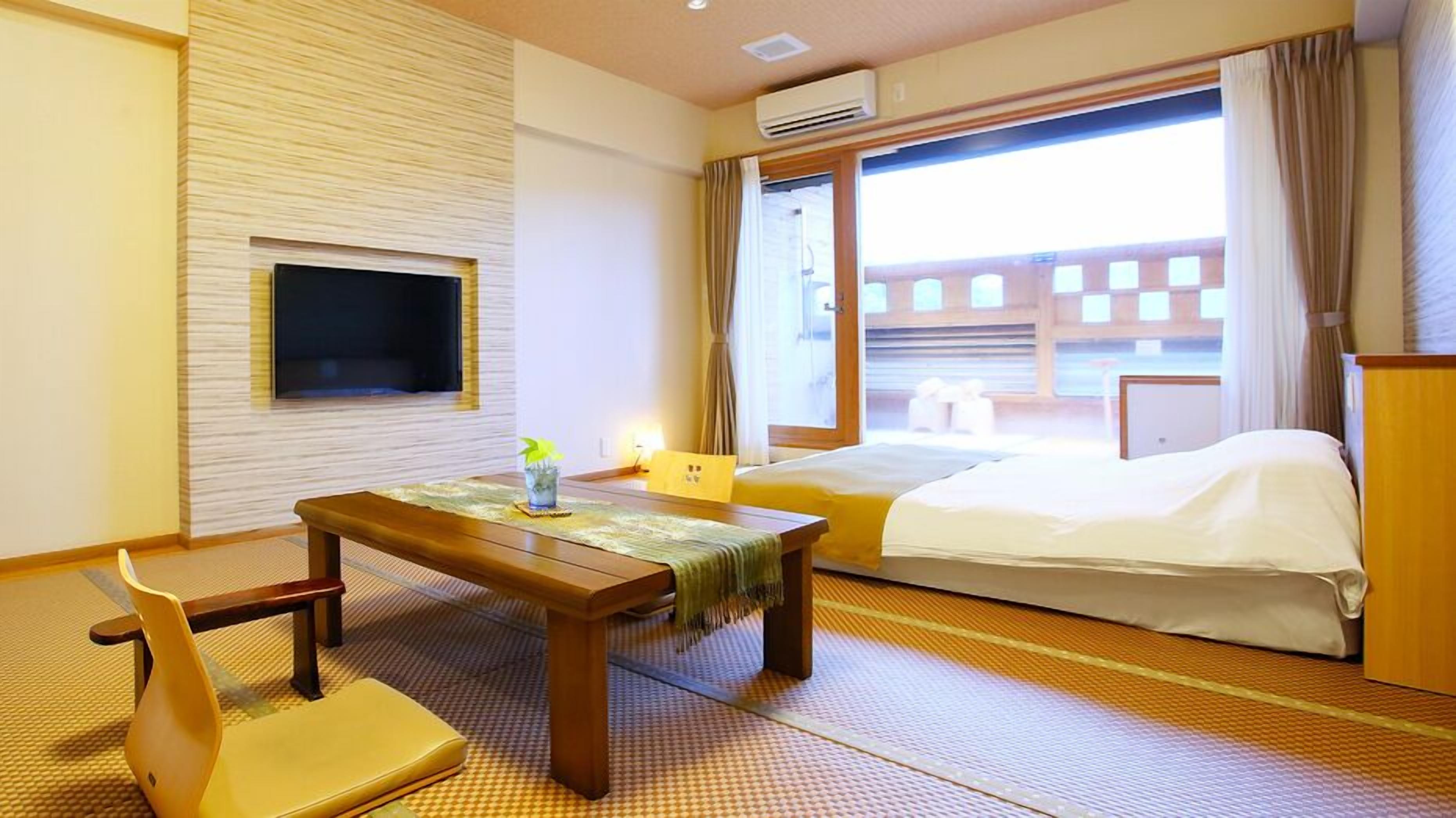 Ein Hotelzimmer mit einem Bett, einem Schreibtisch mit Stuhl, einem Fernseher und einem Fenster mit Vorhängen.