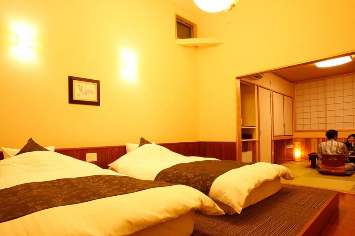 A hotel room with two beds, a small sitting area, and a traditional Japanese-style interior.