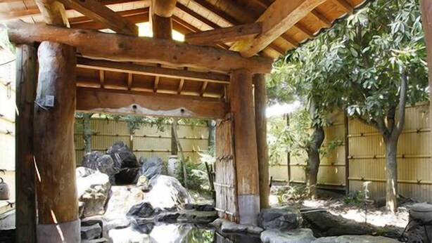 A traditional wooden structure with a pond, rocks, and bamboo fencing. - Yuyuan (Kirishima)