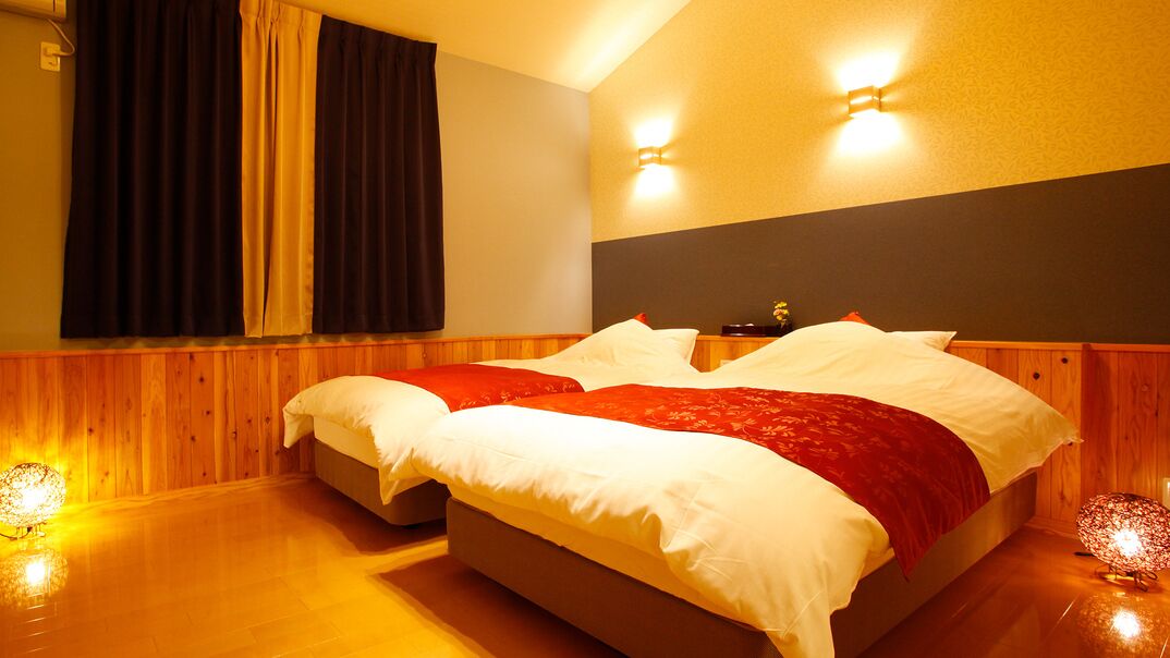 Ein Doppelbett mit weißer und roter Bettwäsche, Holzvertäfelung an den Wänden und zwei Wandleuchten.