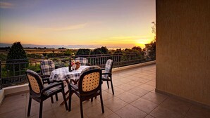 A terrace with a table and chairs, overlooking a scenic landscape during sunset. - Niki Villa (Argaka)