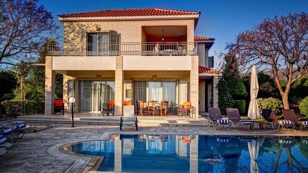 A two-story building with a swimming pool, outdoor seating, and a balcony. - Niki Villa (Argaka)