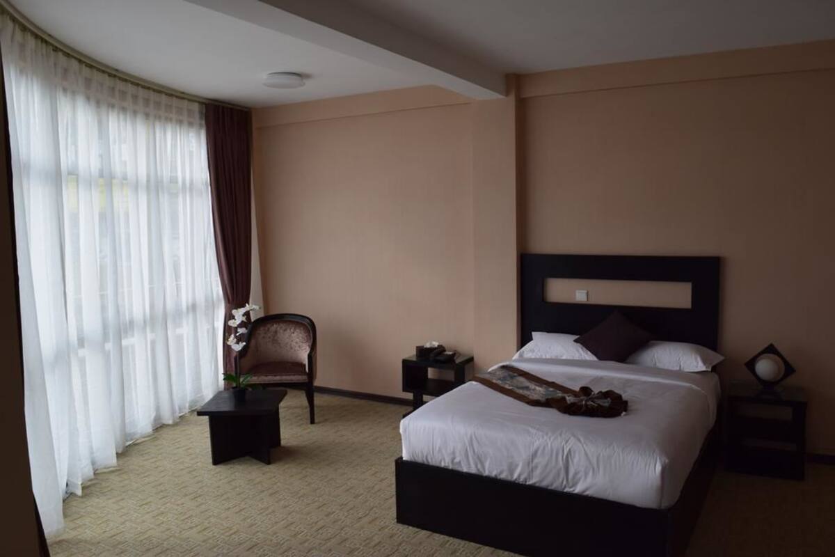A hotel room with a bed, a chair, a small table, and a nightstand.
