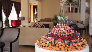 Un hall de hotel con un arreglo floral grande, un área de estar y plantas en macetas.