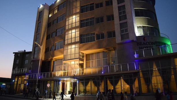 Un hotel de varios pisos con fachada curva, amplias ventanas y un letrero que indica que es el Beacon Hotel.