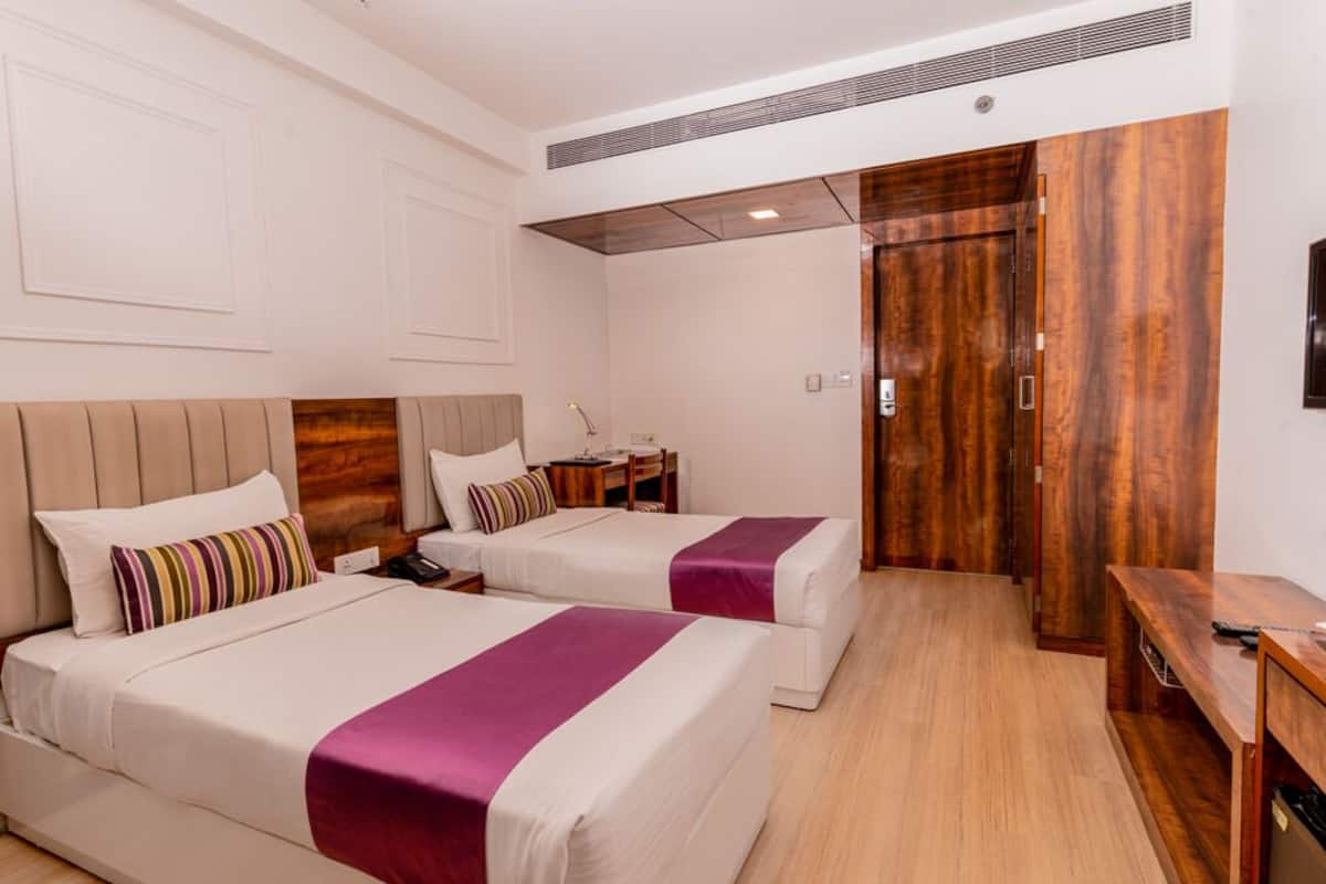 Una habitación de hotel con dos camas, un armario de madera, un escritorio y una mesita.
