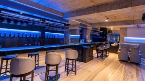 A modern bar area with a long counter, multiple stools, and a seating area with sofas. - Hotel Hardeo (Nagpur)