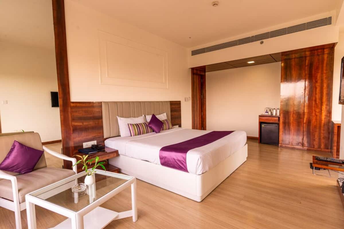 Una habitación de hotel con una cama grande, un sofá, una mesita y un escritorio.