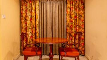 A dining area with a round wooden table and two chairs with red cushions.