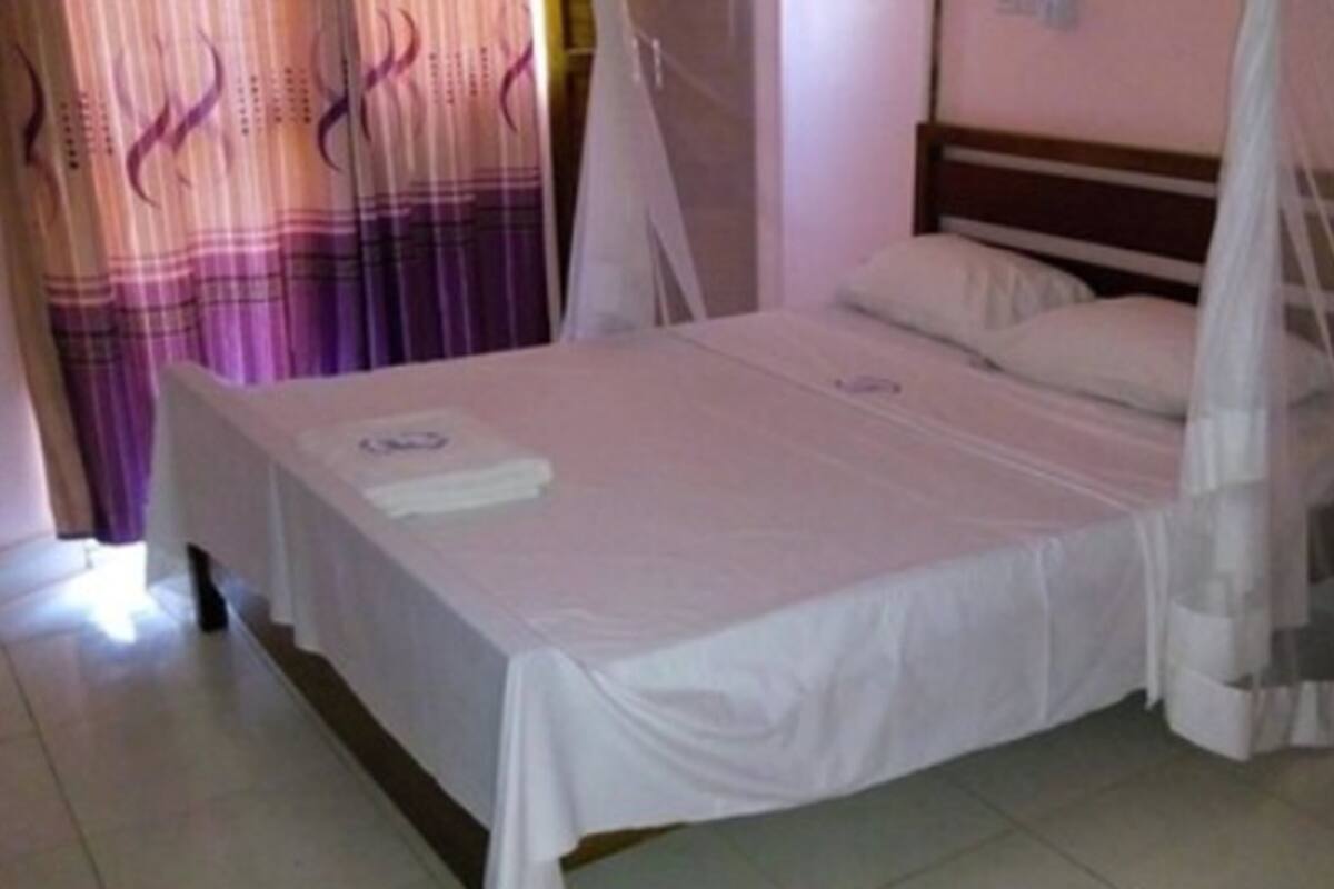 A single bed with a canopy, a bedside table, and a curtain.